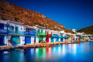 Colorful fisherman houses stand under the mountain on the aegean seashore, summer on the beach of Milos, Greece, Europe