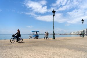 Thessaloniki Greece - April 14 2017 : Woman riding an iBike at the seafront of the northern Greek city of Thessaloniki with ice cream vendor cart in background